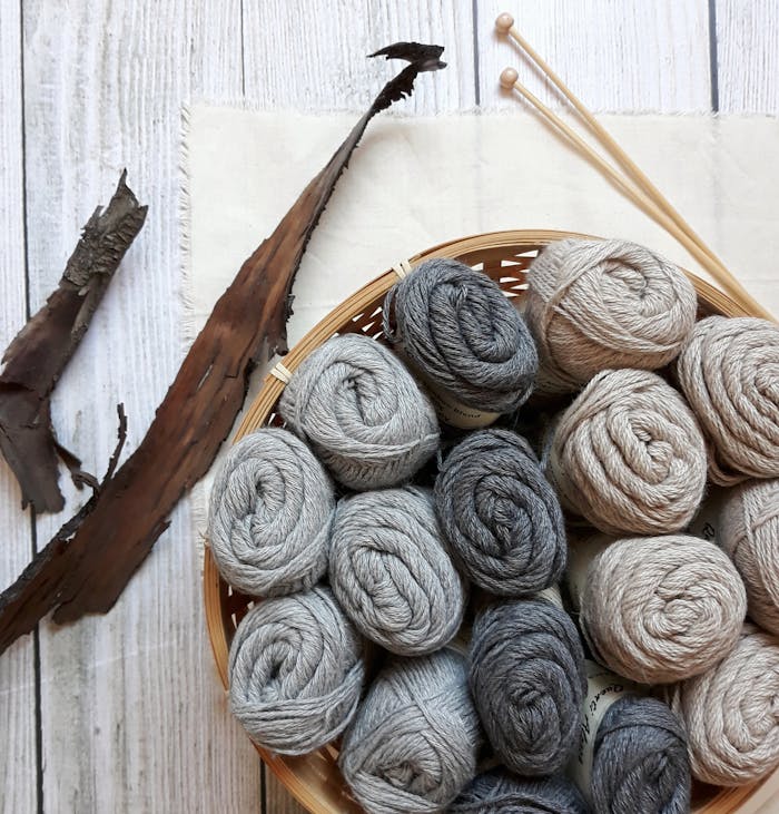Top view of a yarn basket with knitting needles on a wooden surface, perfect for crafting enthusiasts.