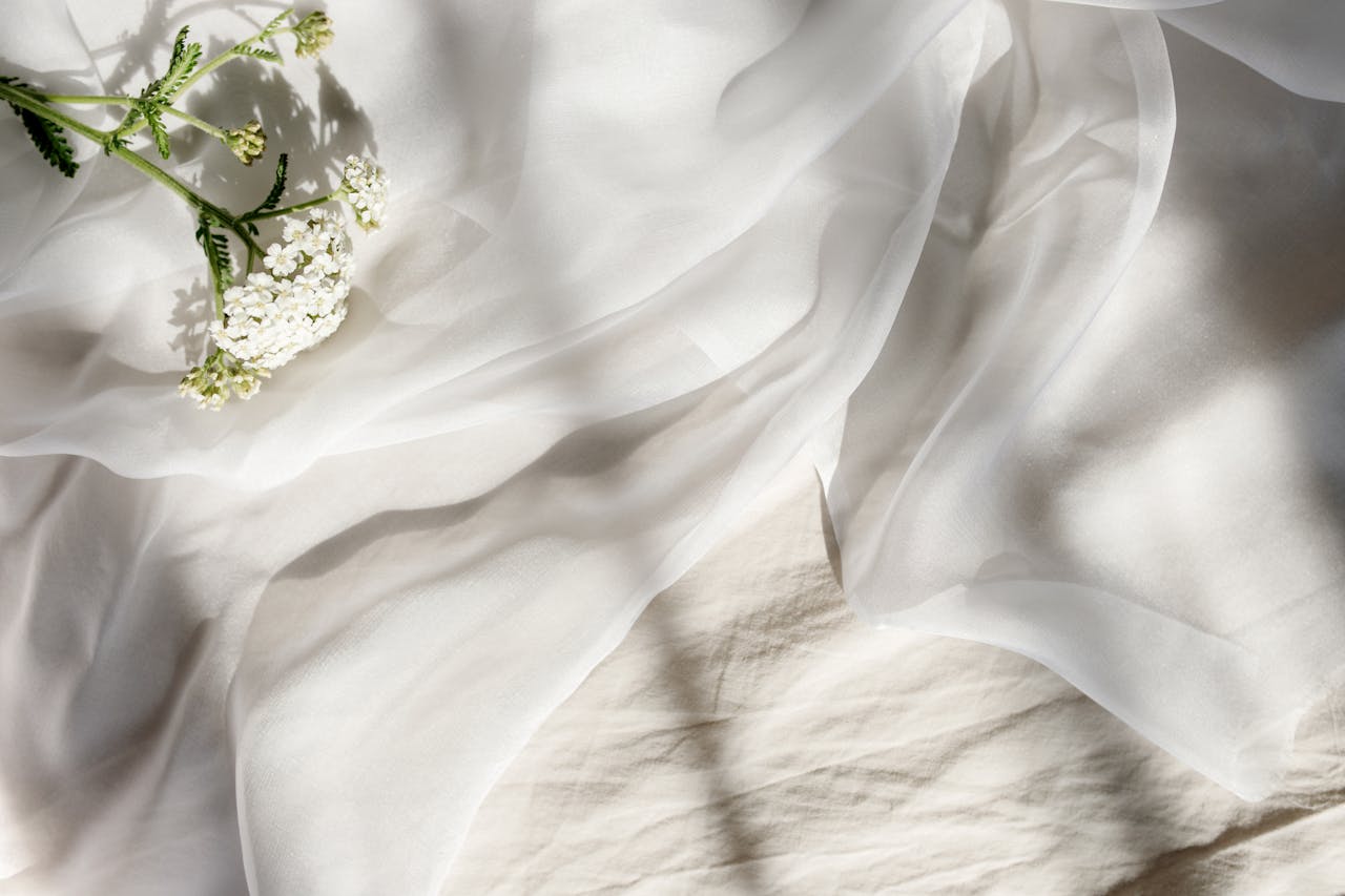 Soft white fabric adorned with delicate flowers, bathed in gentle sunlight.