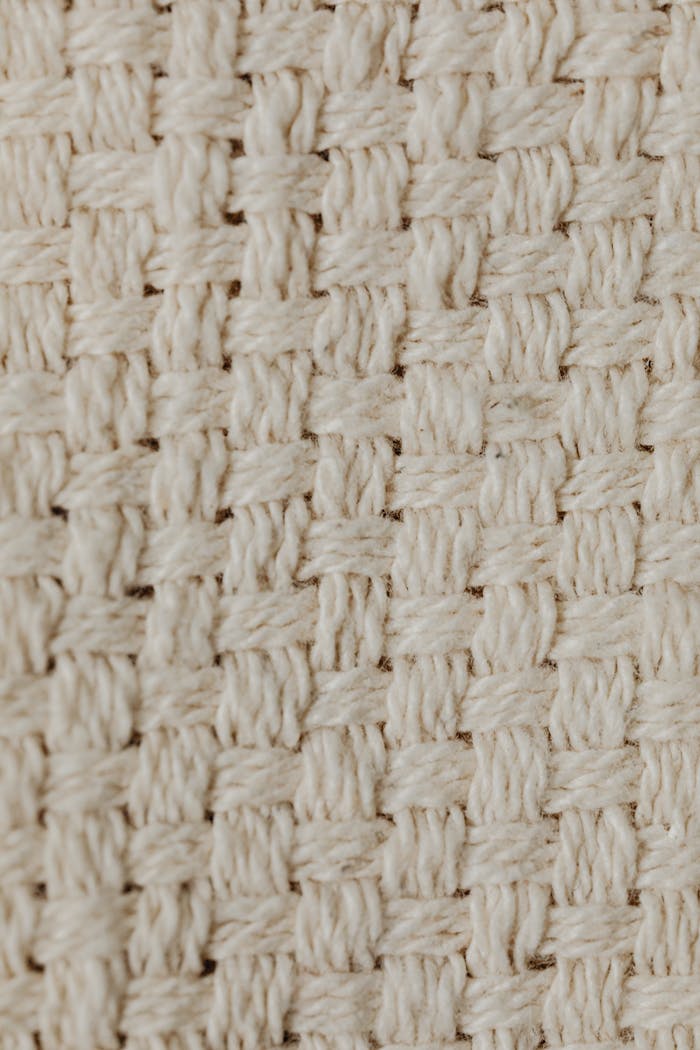 Detailed close-up of a beige knitted fabric showcasing intricate pattern and texture.